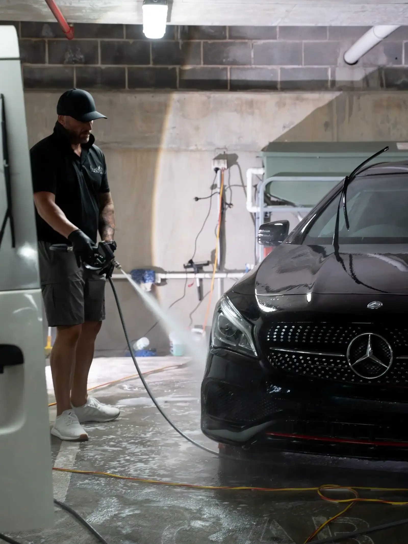 Professional car detailing high-pressure wash on a black Mercedes by Lustrd Detailing in Sydney.